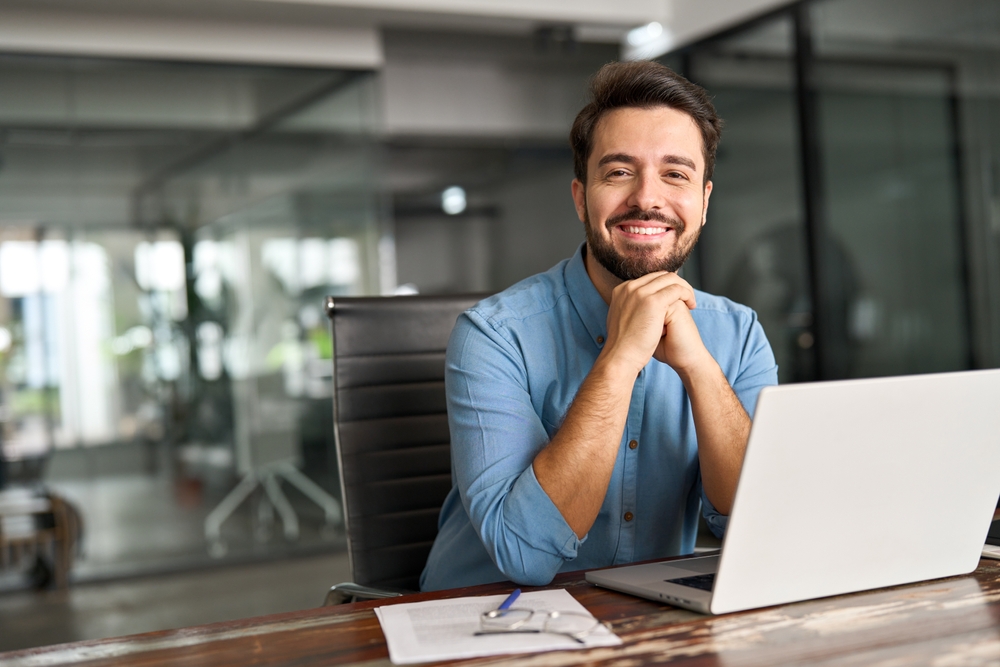 Smiling graduate sitting at laptop