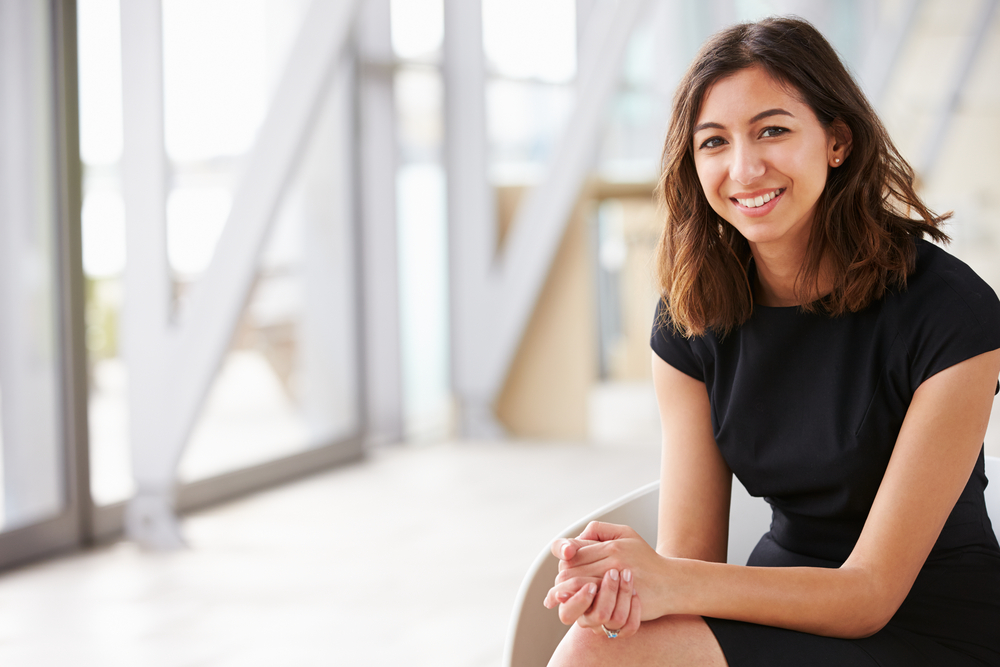 Smiling graduate sitting in office foyer