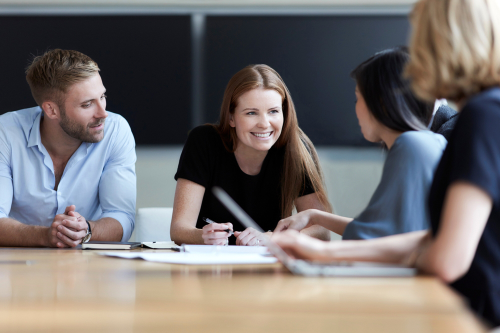 Smiling graduates talking in a meeting