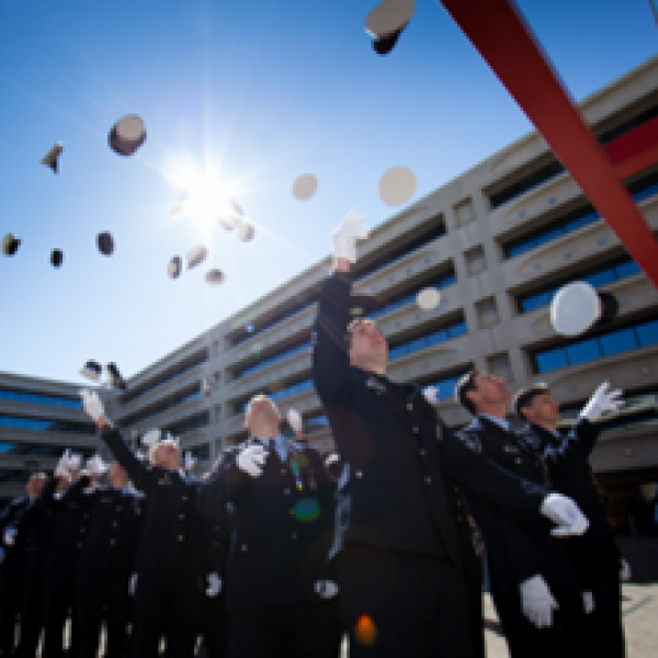 Uniformed officers celebrating and throwing graduation caps