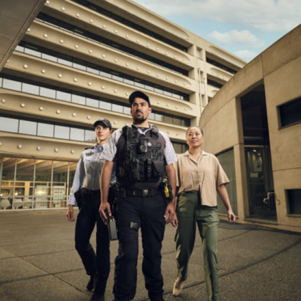 Two uniformed police officers and one plain clothed officer walking towards the camera