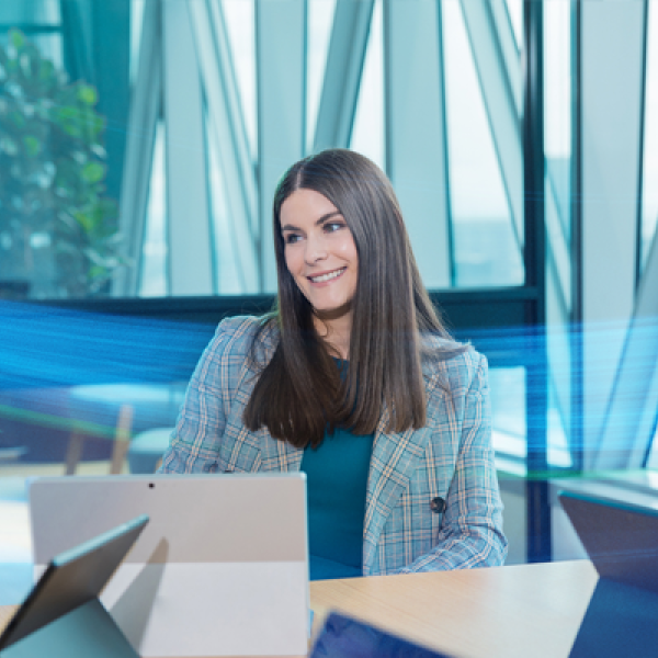 Person in office smiling looking up from a laptop