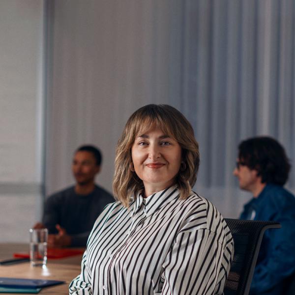 ASD employee Jane smiling at camera sitting a meeting room table