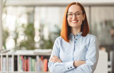 Professional female standing in front of a book case smiling